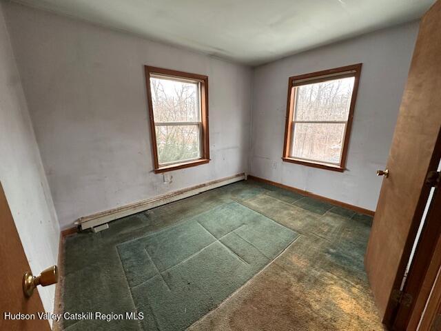 unfurnished room featuring baseboard heating and plenty of natural light