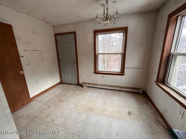 spare room with an inviting chandelier and a baseboard heating unit