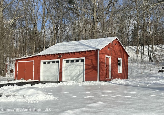 snow covered garage with a detached garage