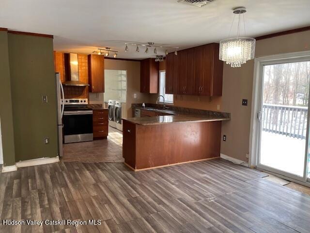 kitchen featuring electric range, wall chimney exhaust hood, separate washer and dryer, kitchen peninsula, and pendant lighting