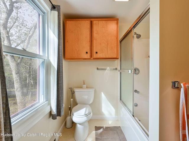 bathroom with toilet and bath / shower combo with glass door