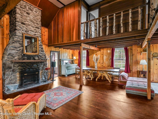 living room featuring a fireplace, wooden walls, hardwood / wood-style floors, and high vaulted ceiling