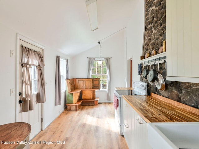 interior space with white electric range oven, wooden counters, vaulted ceiling, decorative light fixtures, and light wood-type flooring