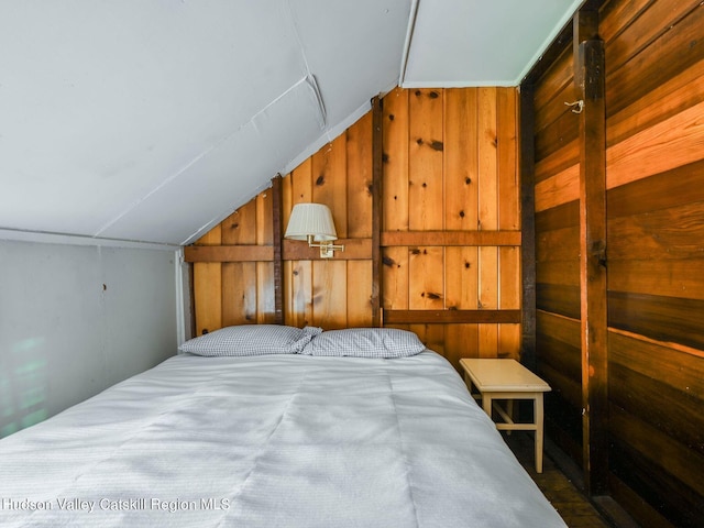 bedroom with wood walls and vaulted ceiling