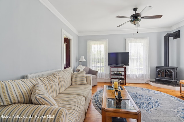 279 Maybie Rd, Gilboa, NY 12076 - living room featuring radiator, a wood stove, a ceiling fan, ornamental molding, and wood finished floors