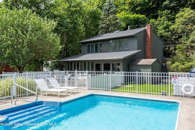 view of swimming pool with a storage unit and a patio