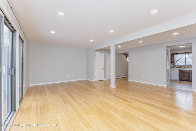 unfurnished living room featuring light hardwood / wood-style flooring and a baseboard heating unit