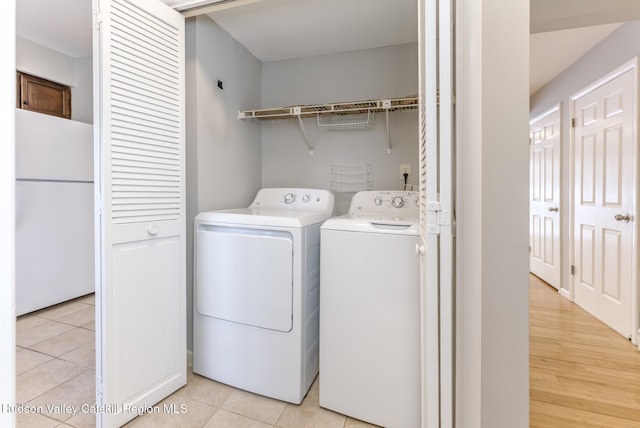 clothes washing area featuring light tile patterned flooring and washing machine and clothes dryer