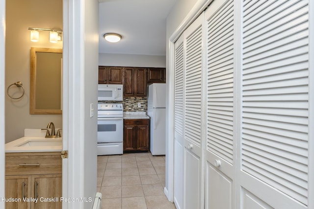 kitchen featuring light tile patterned flooring, sink, backsplash, baseboard heating, and white appliances