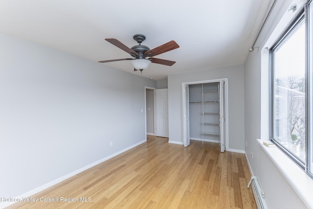 unfurnished bedroom featuring ceiling fan, a baseboard heating unit, a closet, and light wood-type flooring