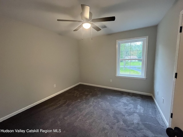 spare room with ceiling fan and dark carpet