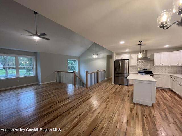 kitchen featuring appliances with stainless steel finishes, white cabinetry, plenty of natural light, and wall chimney range hood