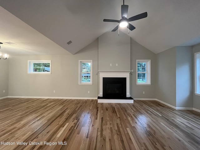 unfurnished living room featuring hardwood / wood-style floors, plenty of natural light, ceiling fan with notable chandelier, and high vaulted ceiling