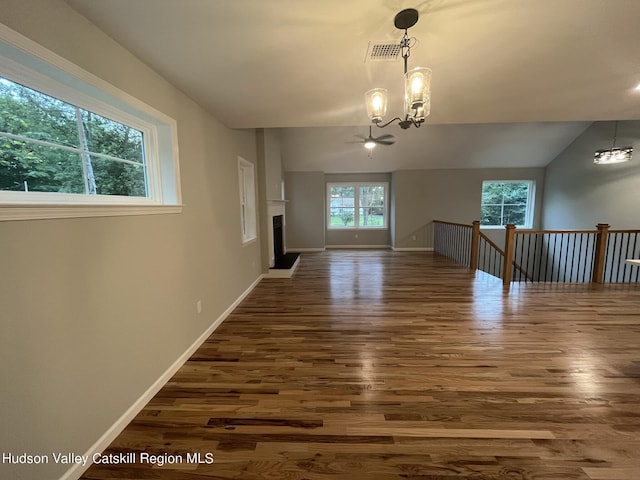 empty room featuring ceiling fan with notable chandelier, lofted ceiling, and dark wood-type flooring