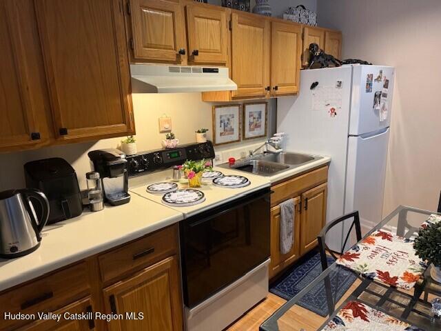 kitchen with white appliances, light hardwood / wood-style floors, and sink