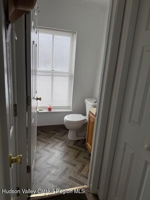 bathroom featuring toilet, vanity, and parquet flooring