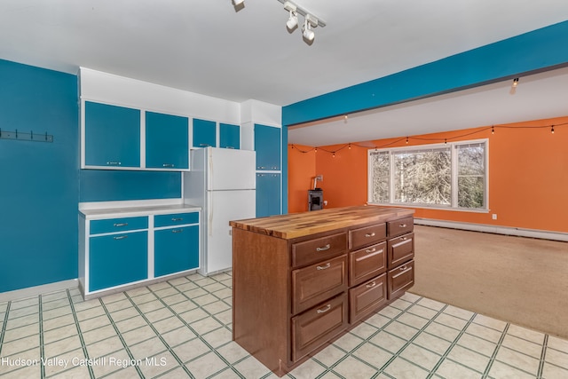 kitchen featuring butcher block countertops, freestanding refrigerator, a baseboard radiator, light carpet, and a center island