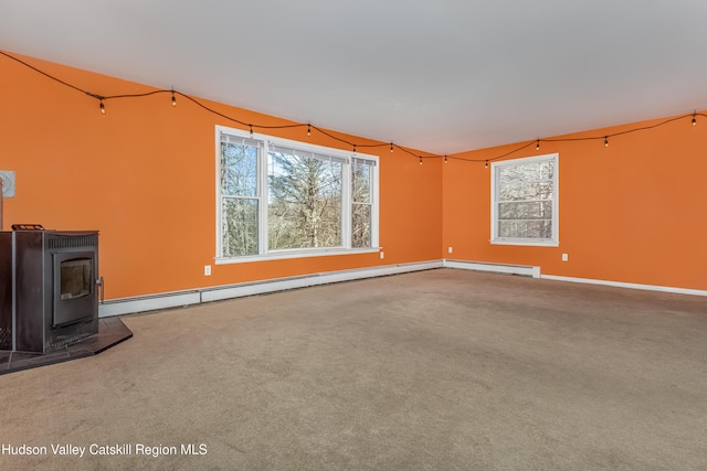 unfurnished living room featuring a wood stove, carpet, baseboards, and a baseboard radiator