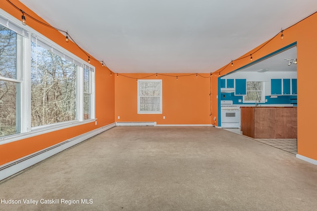 unfurnished living room with baseboards, carpet flooring, baseboard heating, and a sink