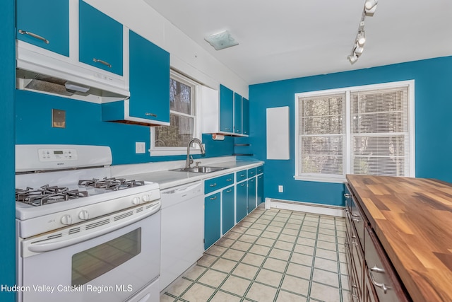 kitchen with a sink, butcher block counters, baseboard heating, white appliances, and blue cabinets