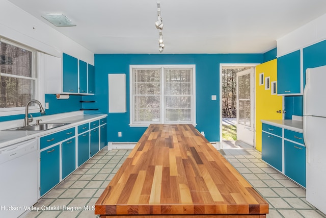 kitchen featuring a sink, white appliances, blue cabinets, a baseboard radiator, and plenty of natural light