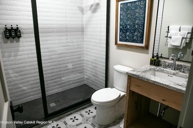 bathroom featuring toilet, a tile shower, and vanity