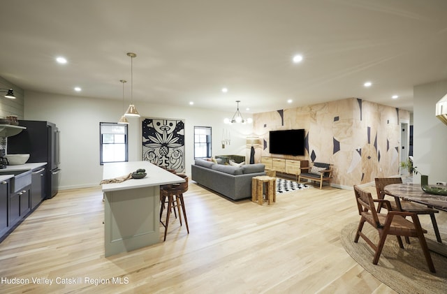 kitchen with hanging light fixtures, a center island, a notable chandelier, a kitchen bar, and light hardwood / wood-style flooring