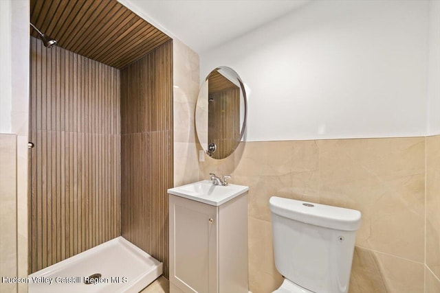 bathroom featuring vanity, a shower, toilet, and tile walls