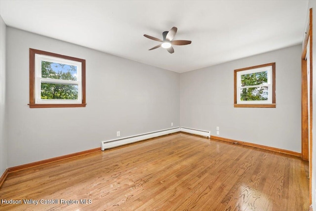 empty room featuring baseboard heating, ceiling fan, a healthy amount of sunlight, and light wood-type flooring