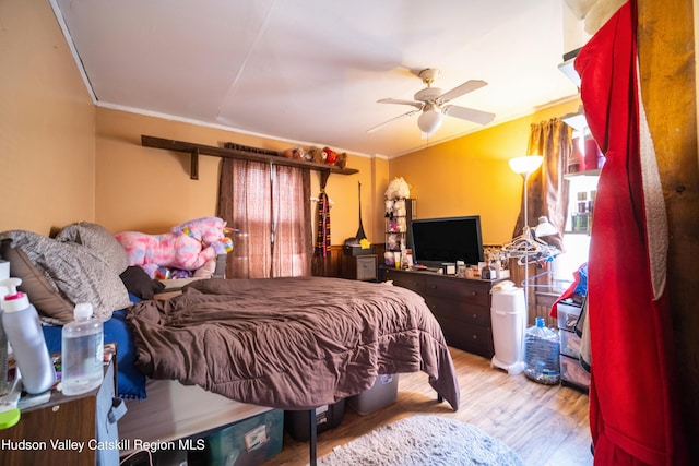 bedroom featuring a ceiling fan, crown molding, and wood finished floors