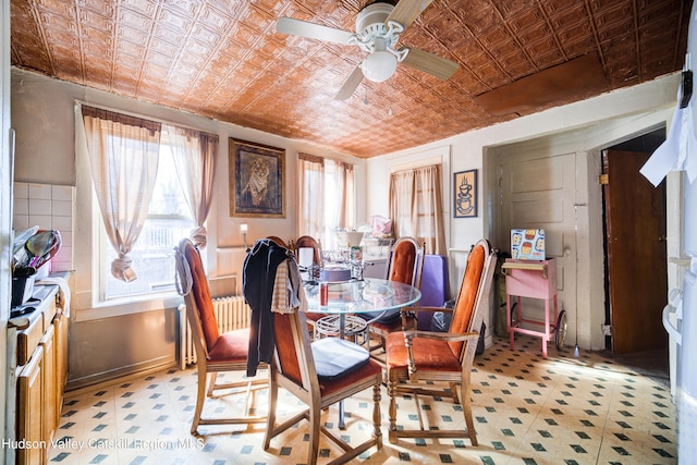 dining space featuring ceiling fan, light floors, and an ornate ceiling