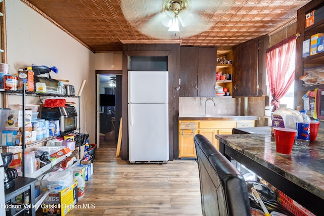 kitchen featuring an ornate ceiling, freestanding refrigerator, light wood finished floors, and open shelves