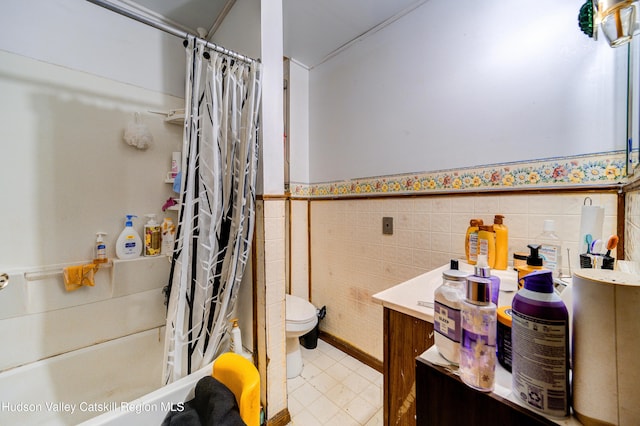 full bathroom with toilet, a wainscoted wall, shower / tub combo with curtain, tile patterned floors, and tile walls