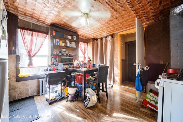 dining room with radiator heating unit, wood finished floors, an ornate ceiling, and a ceiling fan