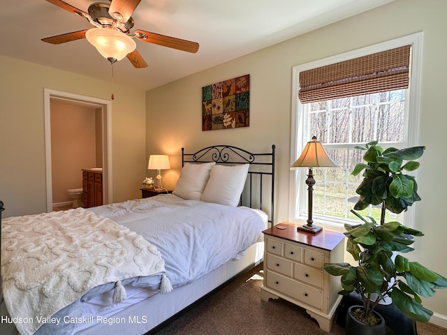 bedroom with ensuite bathroom, dark colored carpet, and ceiling fan