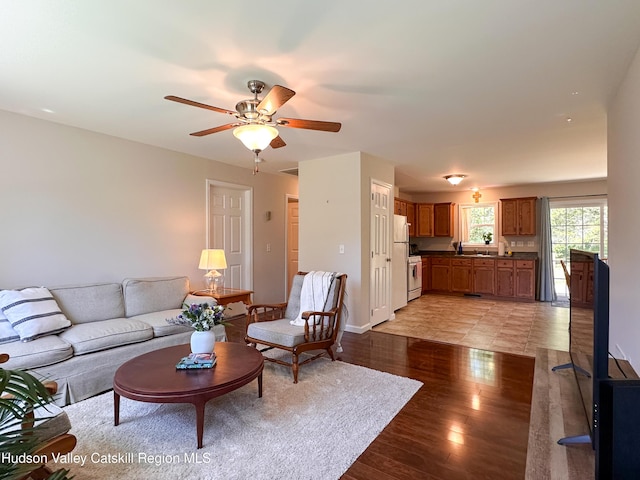 living room with light wood-style floors, baseboards, and a ceiling fan