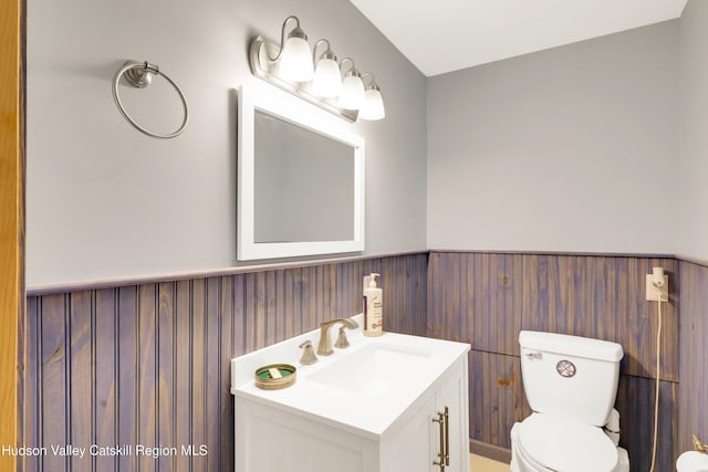 bathroom with vanity, toilet, and a wainscoted wall