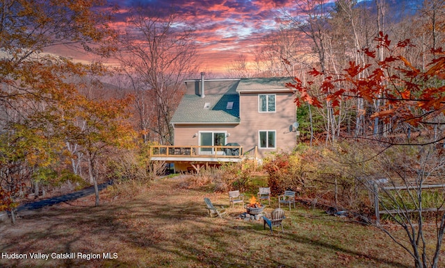 back house at dusk with a deck and a yard