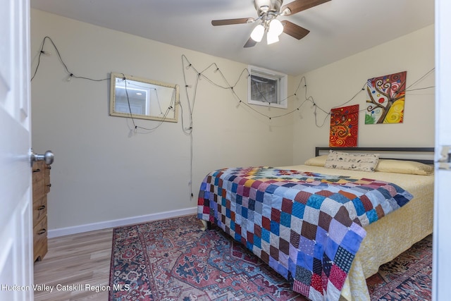 bedroom with a wall mounted air conditioner, ceiling fan, and wood-type flooring