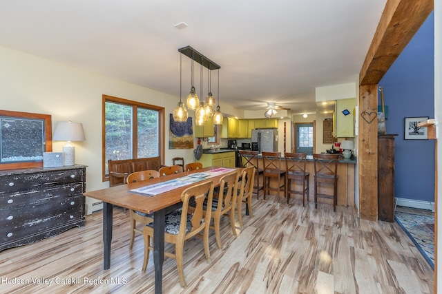 dining space featuring ceiling fan, beamed ceiling, a baseboard radiator, and light wood-type flooring