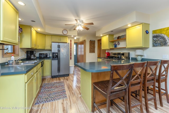 kitchen with sink, stainless steel appliances, light hardwood / wood-style flooring, kitchen peninsula, and a kitchen bar