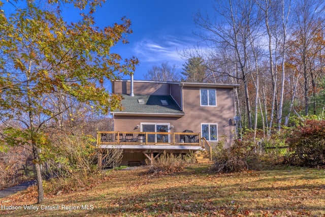 rear view of property featuring a deck and a lawn