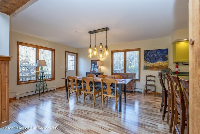 dining space featuring light wood-type flooring, a baseboard radiator, and an inviting chandelier