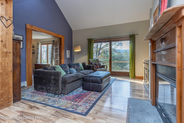 living room featuring a wealth of natural light, wood-type flooring, vaulted ceiling, and a baseboard heating unit