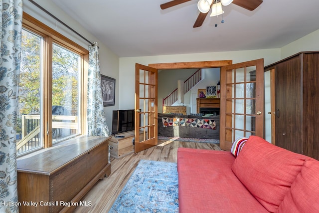 living room featuring ceiling fan, french doors, and light wood-type flooring