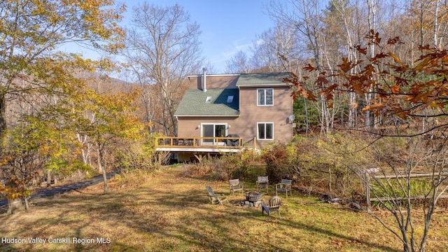 back of property featuring a deck, an outdoor fire pit, and a lawn