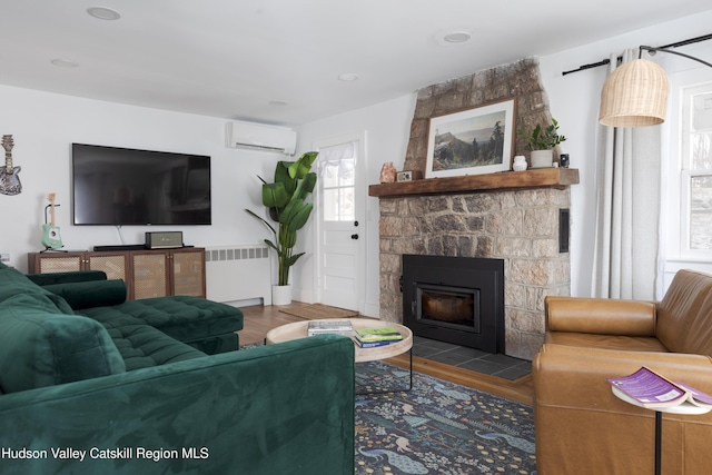 living room featuring wood-type flooring, a stone fireplace, radiator heating unit, and a wall mounted AC