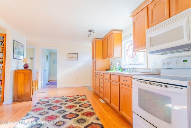 kitchen with light brown cabinets, white appliances, light countertops, and light wood-style floors