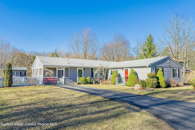 ranch-style home with a front lawn, fence, and a sunroom