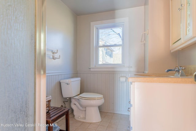 bathroom with tile patterned flooring, wainscoting, toilet, and vanity